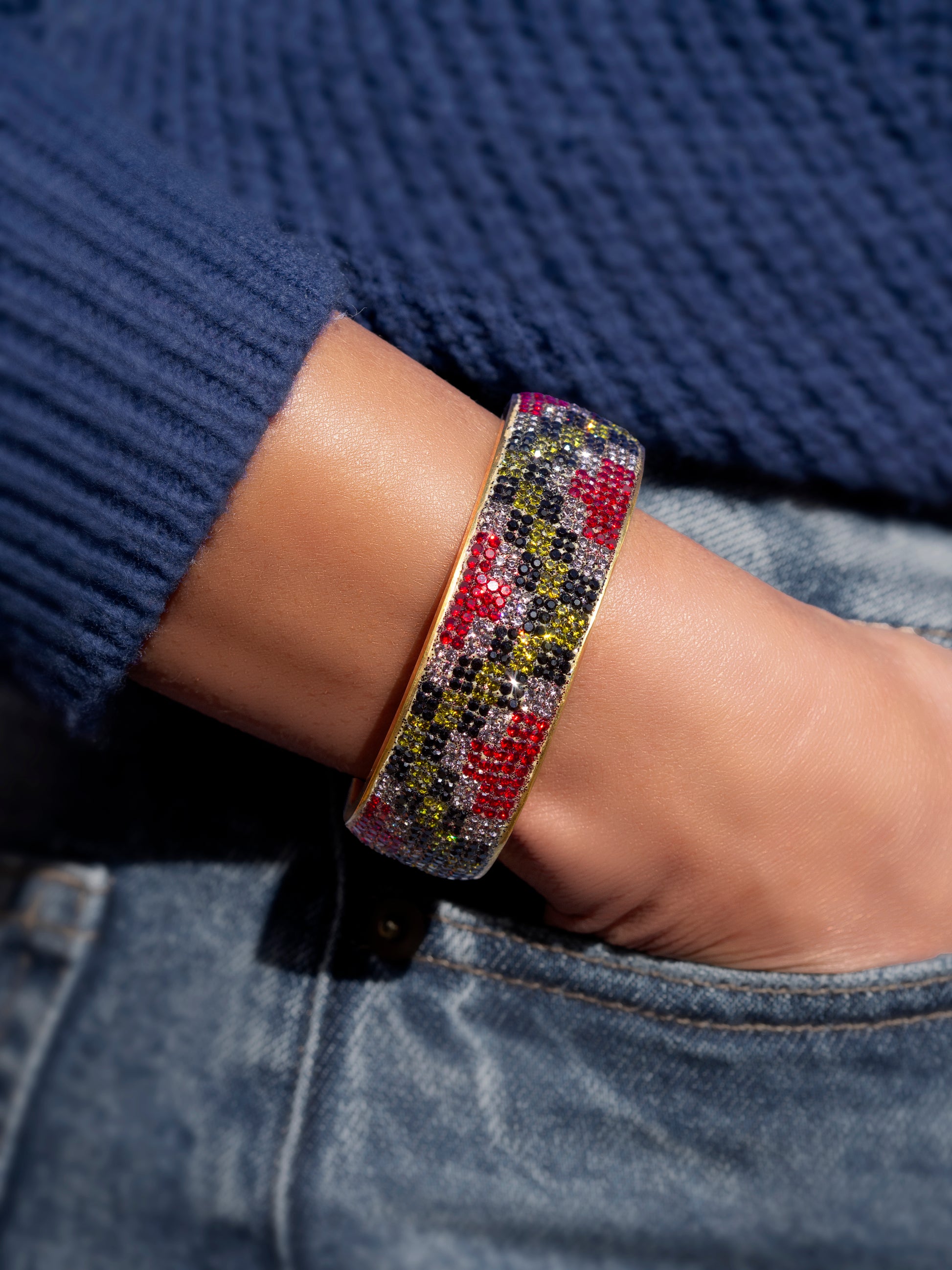 80DB Empress Crescendo cuff featuring a bold checkered pattern in black, red and grey with light -reactive green crystals creating a dynamic play of colour.